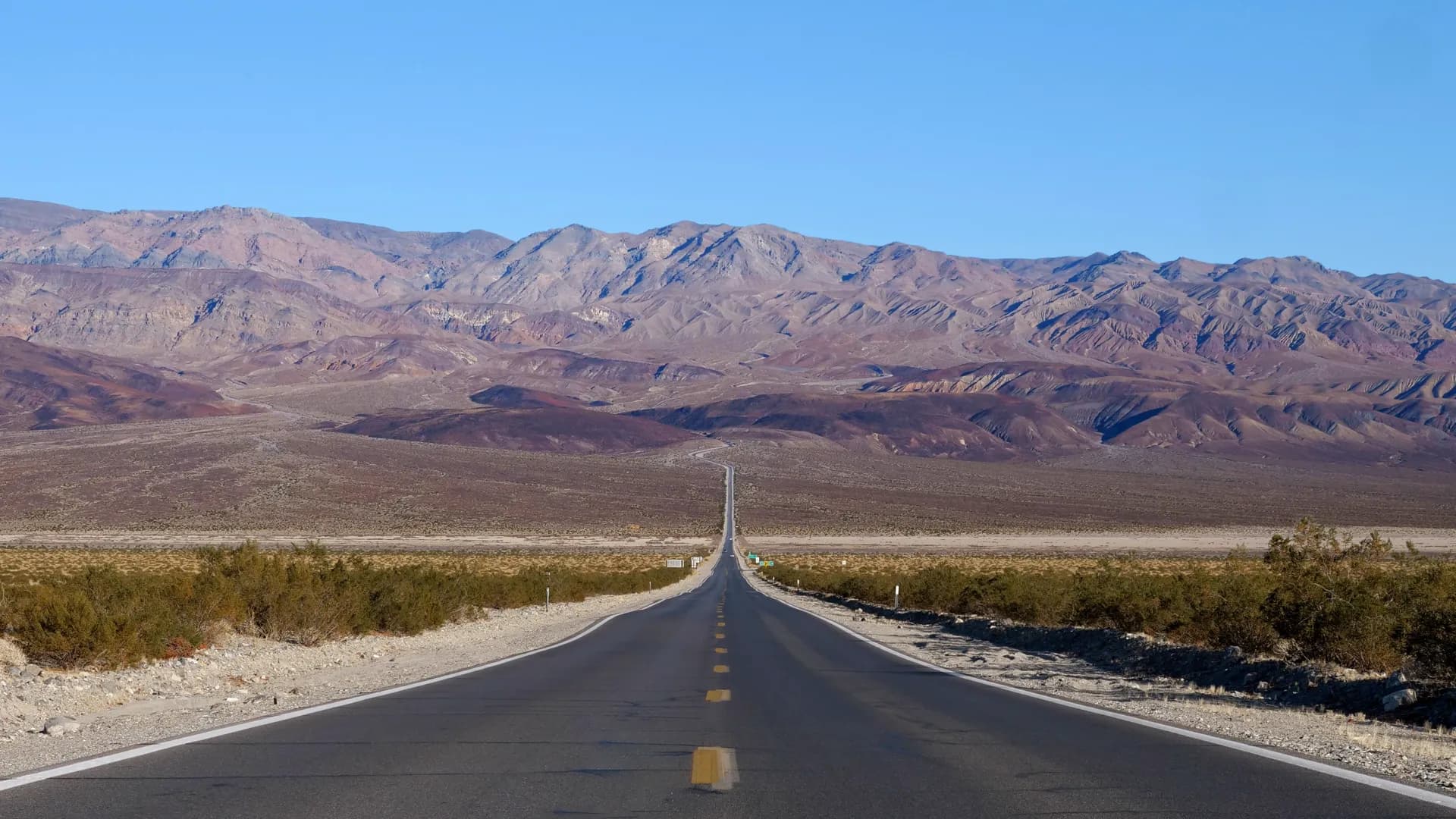 Carretera recta que cruza el desierto hacia las montañas